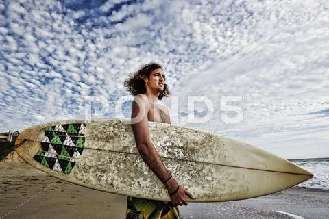 Caucasian Man Carrying Surfboard On Beach