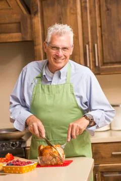 Caucasian man carving chicken in kitchen Stock Photos