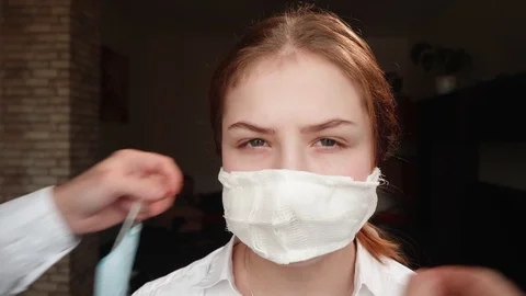 Caucasian man changes homemade face mask to factory medical mask on girl's face Stock Footage 125095027