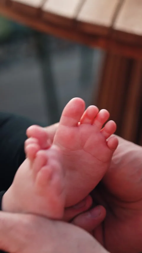 Caucasian man clapping the tiny feet of a baby.  Video stock 309768290