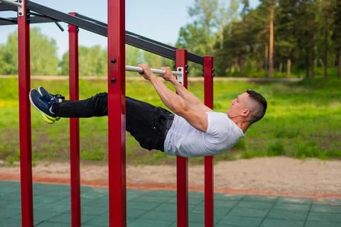 Caucasian man doing a back plank on the uneven bars. Workout on the sports 库存照片