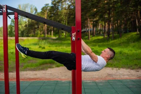 Caucasian man doing a back plank on the uneven bars. Workout on the sports 库存照片
