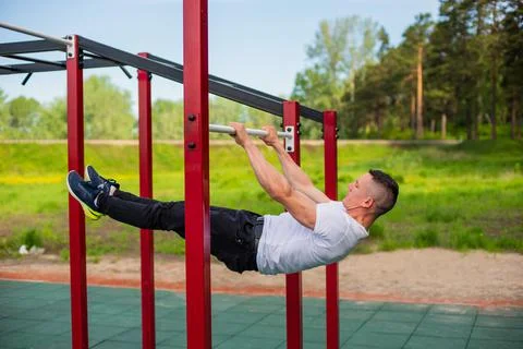 Caucasian man doing a back plank on the uneven bars. Workout on the sports 库存照片