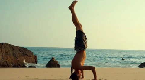 Caucasian man doing head stand on the beach Stock Footage 61955420
