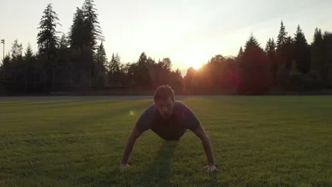 Caucasian man doing pushups in a field at sunset. 4K 24FPS. Stock Footage 140952210