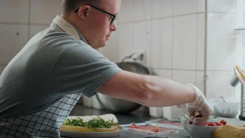 Caucasian man with down syndrome preparing a sandwich in commercial kitchen Stock-Footage 202074729