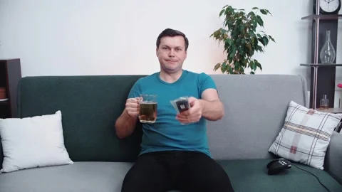 Caucasian man drinks beer while watching TV switching channels. Stock Footage 146395967