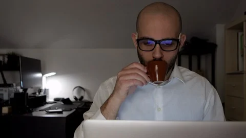 Caucasian man drinks coffee while working on computer in his home office Stock Footage 127442671