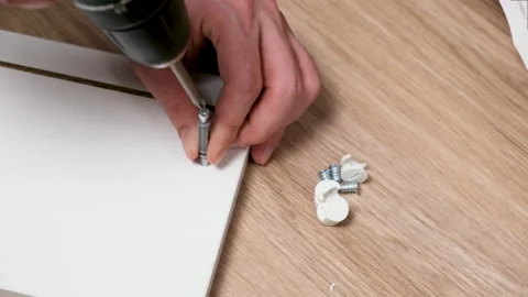 Caucasian man drives hex socket screw drive with electric powered drill or screw Stock Footage 163246769