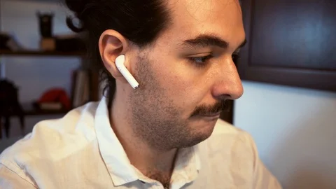  Caucasian man during a remote work session is using the bluetooth earphone in f Stock Footage 130007472