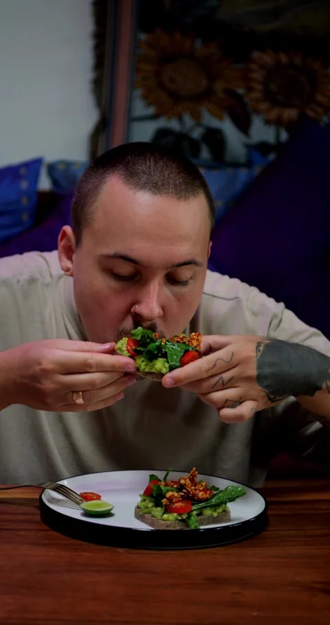 Caucasian Man Enjoys or Eats Almond Bread with Avocado, Arugula and Tomato Stock Footage 286812179