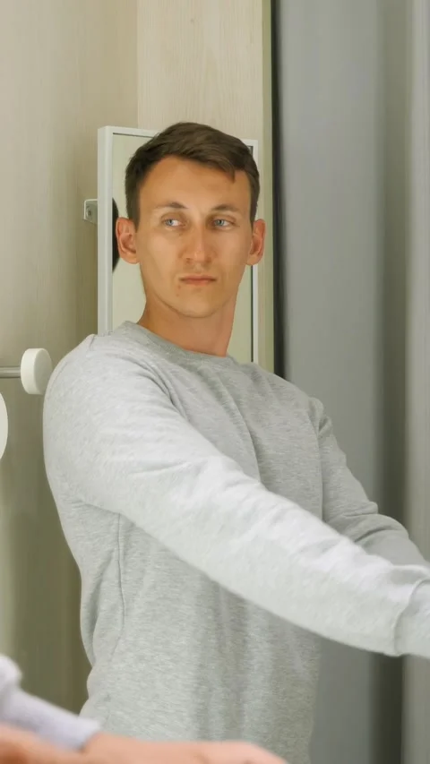 Caucasian Man In Fitting Room Trying Sweater And Checking Reflection, Neutral Vídeos de archivo 333791297