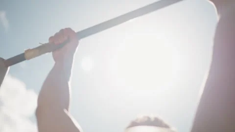 Caucasian man grabbing pullup bar under bright sun, muscular arm reach from low Stock Footage 323505320