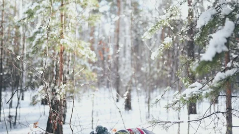 A Caucasian man in a gray hat and sweater standing in the winter forest, making Stock Footage 128002178