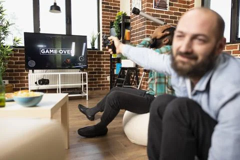 Caucasian man holding wireless controller gestures dramatically at tv screen Stock Photos