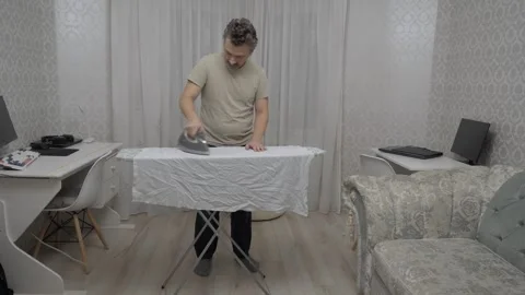 Caucasian man ironing Stockbeeldmateriaal 336340971