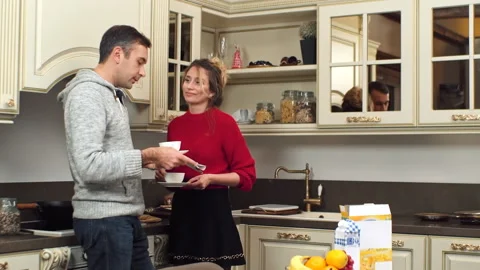 A caucasian man in jacket drinking coffee and reading a newspaper on a kitchen. Stock Footage 145141959