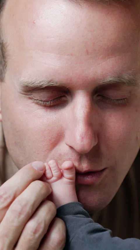 Caucasian man kisses tenderly tiny infant's foot.  Stock Footage 305168344