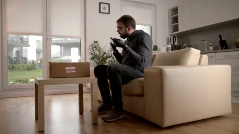 Caucasian Man Laying Down Package On A Coffee Table In His Open Plan Living Room Stock Footage 140258048