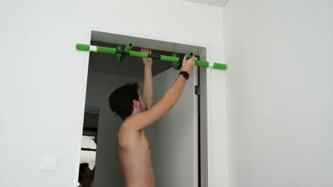 Caucasian man mounts a pull-up bar at home and starts exercising. Stock Footage 150550652