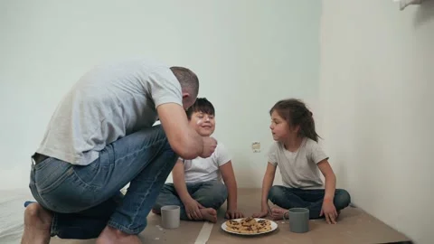 A Caucasian man paints a boy and a girl with a brush The father paints on his Stock Footage 153282053