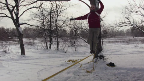 Caucasian man practicing slackline in the winter forest. 스톡 동영상 147159455