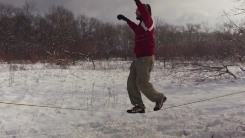 Caucasian man practicing slackline in the winter forest. 스톡 동영상 147160752