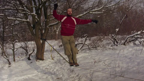 Caucasian man practicing slackline in the winter forest. 스톡 동영상 147160882