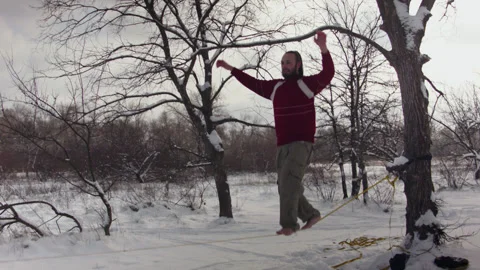 Caucasian man practicing slackline in the winter forest. 스톡 동영상 147162041