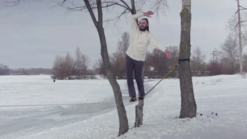 Caucasian man practicing slackline in the winter forest. Stock Footage 148300532