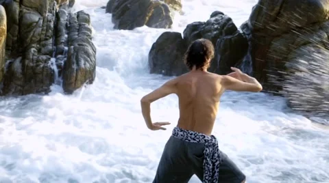 Caucasian man practicing  tai chi inside pacific ocean waves Stock Footage 61955681