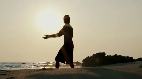 Caucasian man practicing  tai chi on the beach at sunset Stock Footage 61955710