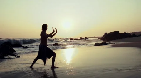 Caucasian man practicing  tai chi on the beach at sunset Stock Footage 61955829
