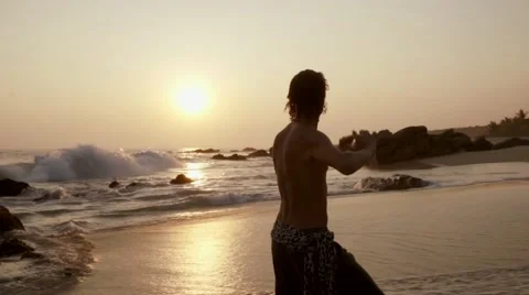 Caucasian man practicing  tai chi on the beach at sunset Stock Footage 61955897
