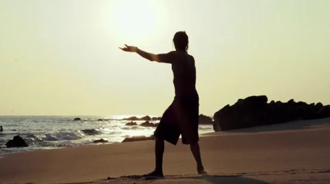 Caucasian man practicing  tai chi on the beach at sunset Stock Footage 61956095