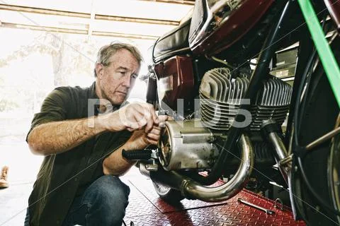 Caucasian man repairing motorcycle in garage Stock Photos