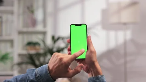 Caucasian man scrolls sideways and taps the green screen of a smartphone with Video stock 249188569