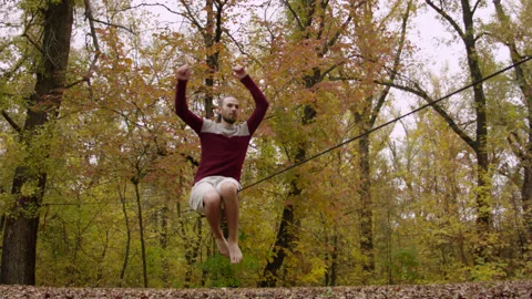 Caucasian man sets slackline between trees in the autumn forest. 스톡 동영상 142093852