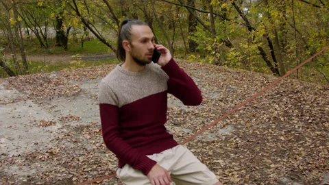 Caucasian man sets slackline between trees in the autumn forest. 스톡 동영상 142116829