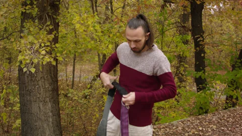 Caucasian man sets slackline between trees in the autumn forest. 스톡 동영상 142124651