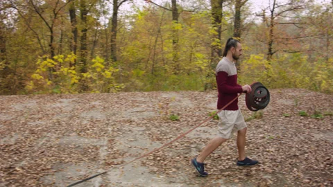 Caucasian man sets slackline between trees in the autumn forest. 스톡 동영상 142126590