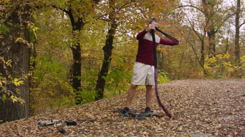 Caucasian man sets slackline between trees in the autumn forest. 스톡 동영상 142127185
