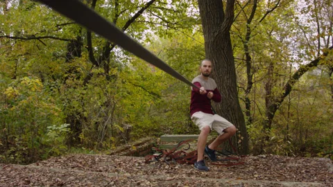 Caucasian man sets slackline between trees in the autumn forest. 스톡 동영상 142127338