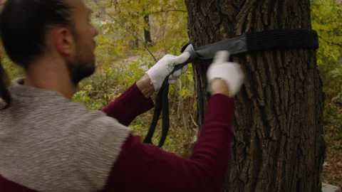 Caucasian man sets slackline between trees in the autumn forest. 스톡 동영상 142131587