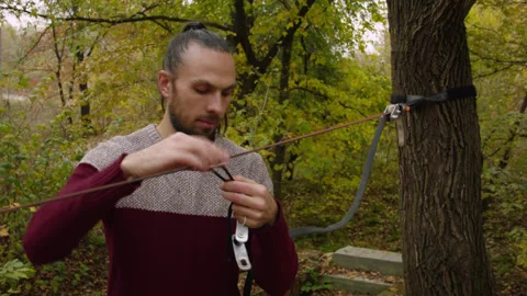 Caucasian man sets slackline between trees in the autumn forest. 스톡 동영상 142271471