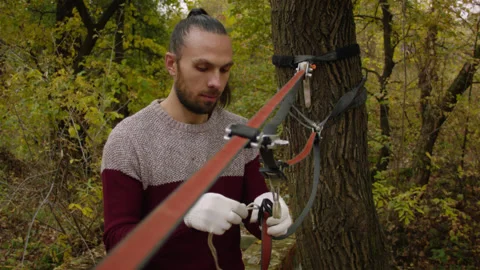 Caucasian man sets slackline between trees in the autumn forest. 스톡 동영상 142271542
