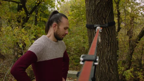 Caucasian man sets slackline between trees in the autumn forest. 스톡 동영상 142271638