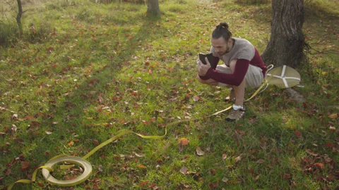 Caucasian man sets slackline between trees in the autumn forest. 스톡 동영상 142283973