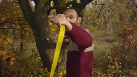 Caucasian man sets slackline between trees in the autumn forest. 스톡 동영상 142300545