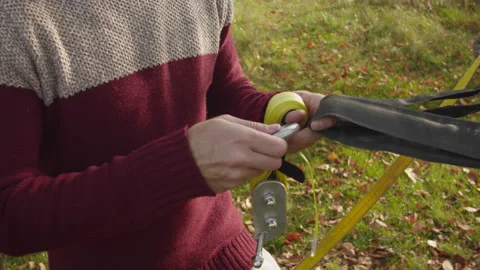 Caucasian man sets slackline between trees in the autumn forest. 스톡 동영상 142301696
